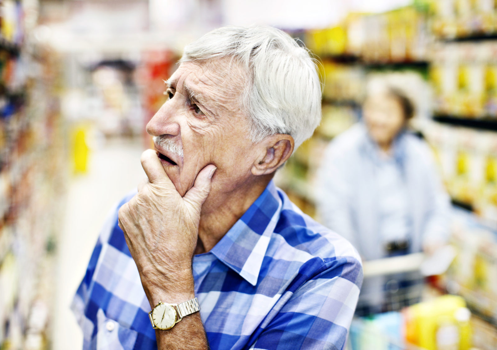 Senior man shopping at grocery store trying to remember what it is he's supposed to get