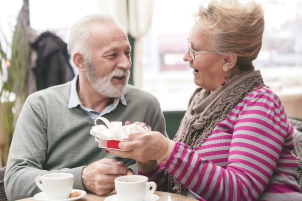 Elder woman giving elder man a gift in an assisted living community