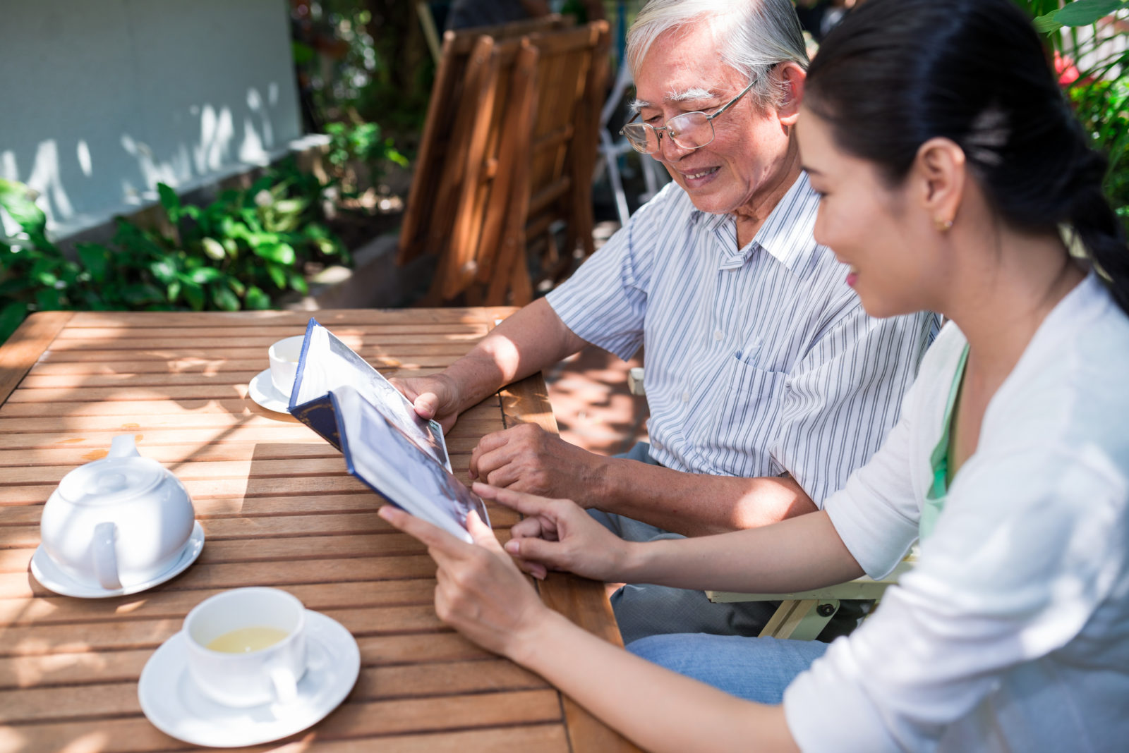 Asian father and daughter looking at old photos in photo album