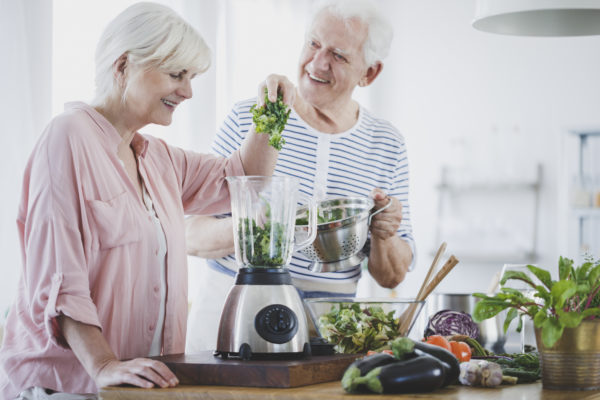 Happy elderly woman and her husband preparing vegan smoothie
