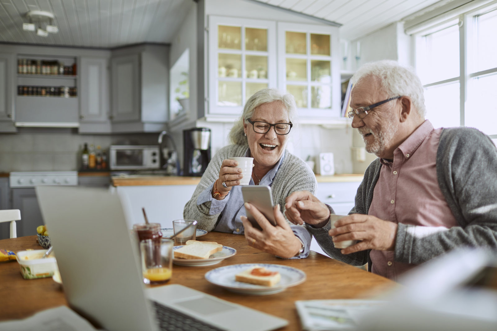 Close up of a senior couple using a smartphone and having breakfast