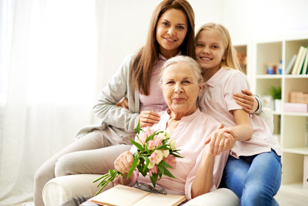 Happy senior woman holding flowers with her loving daughter and granddaughter on Mother's Day