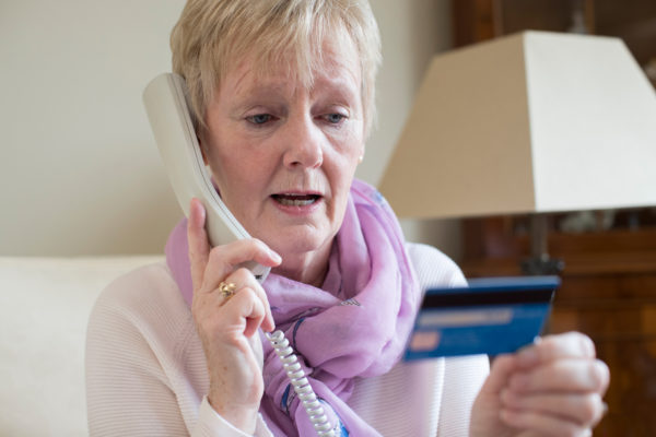 senior woman with credit card in hard talking on the phone