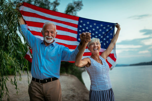 Shot of a happy senior couple walking by the river with an American flag