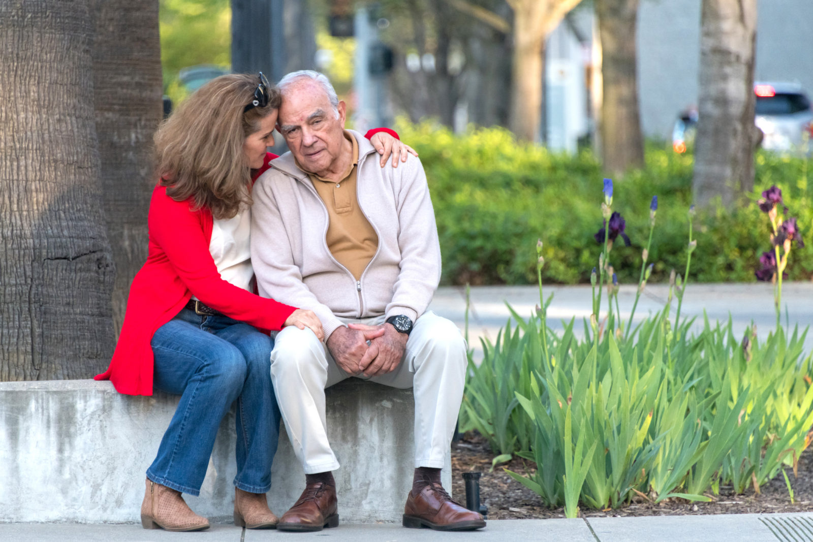 senior man with dementia being comforted by daughter in outdoor setting