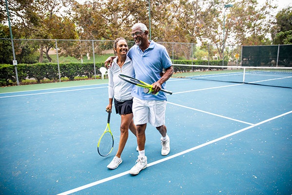 older couple waking off tennis court after playing