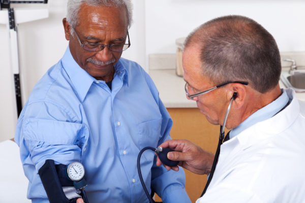 elderly man getting blood pressure taken at doctor's office