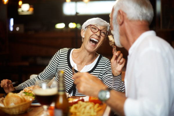 elderly woman eating with husband and laughing