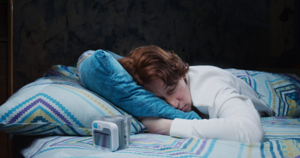 Mature woman is sleeping in bed having wrist blood pressure monitor next to pillow