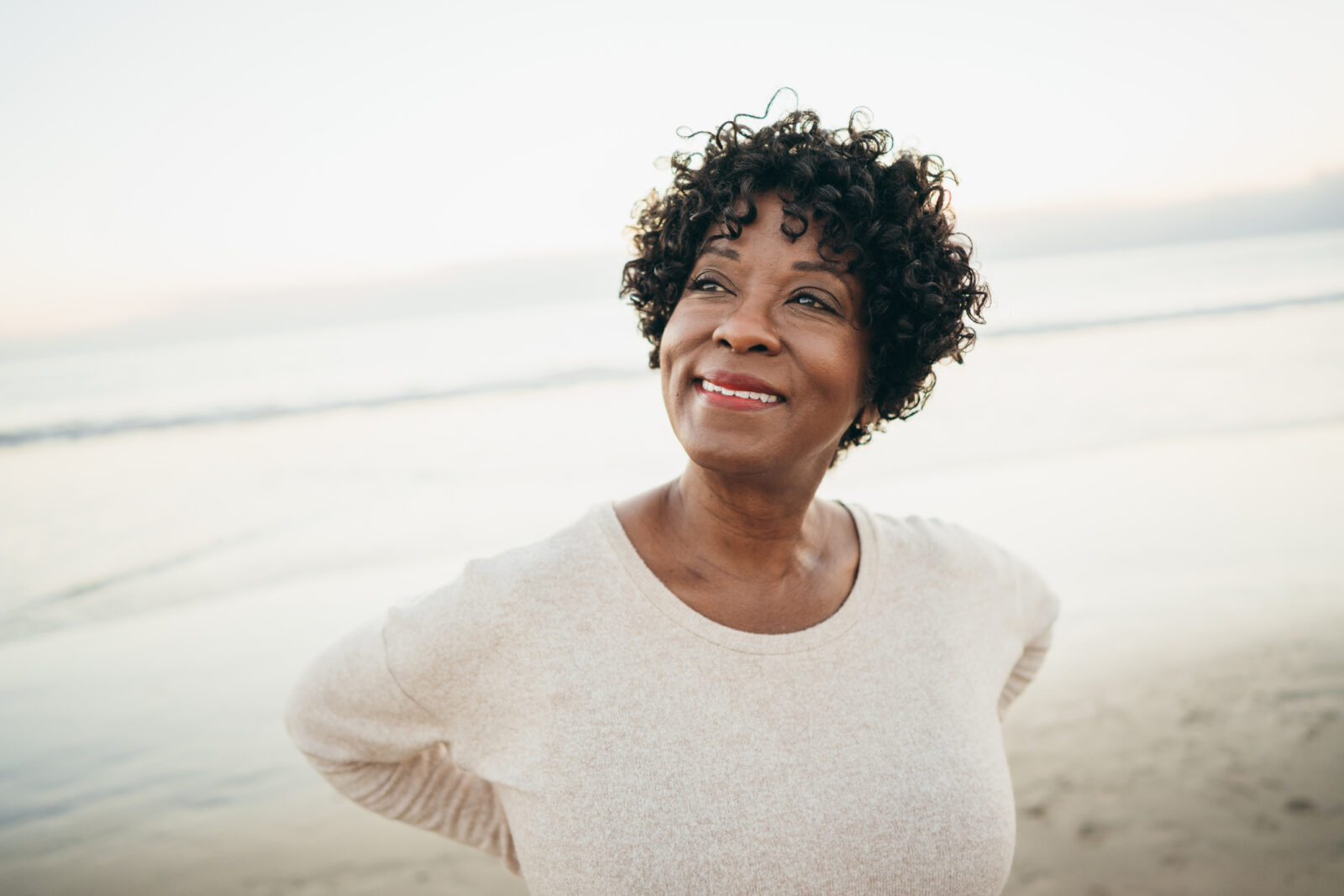 Senior Black woman looking upwards and smiling.