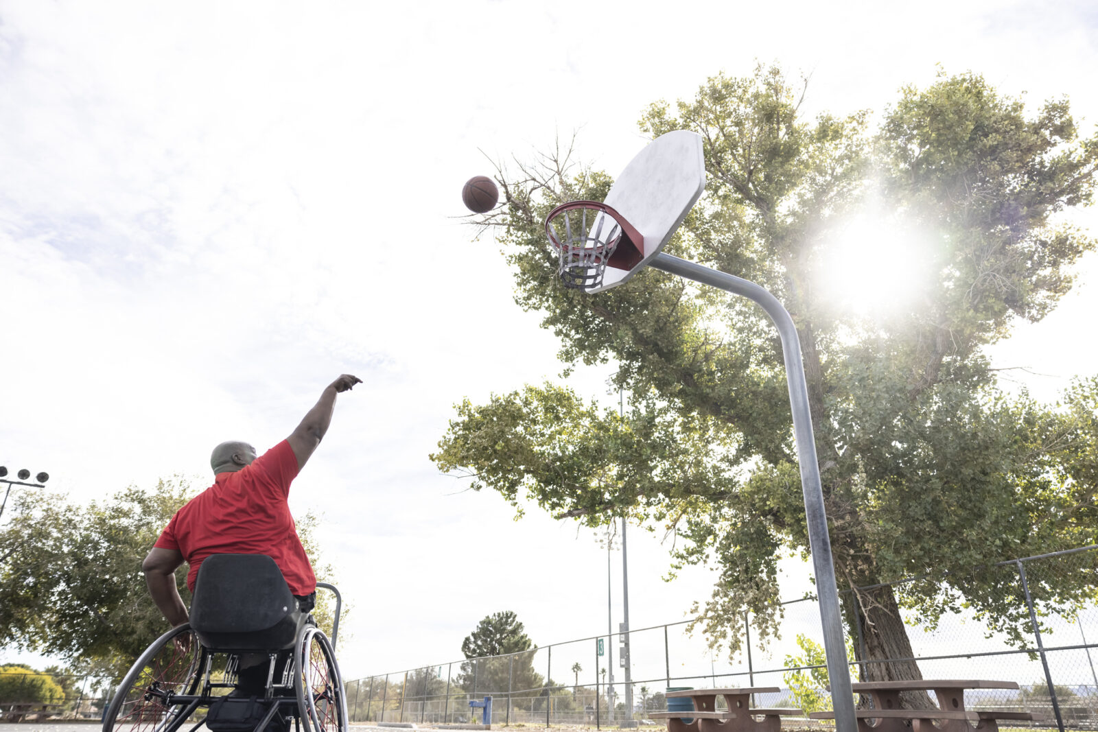 An African American practicing wheelchair basketball skills at the local park