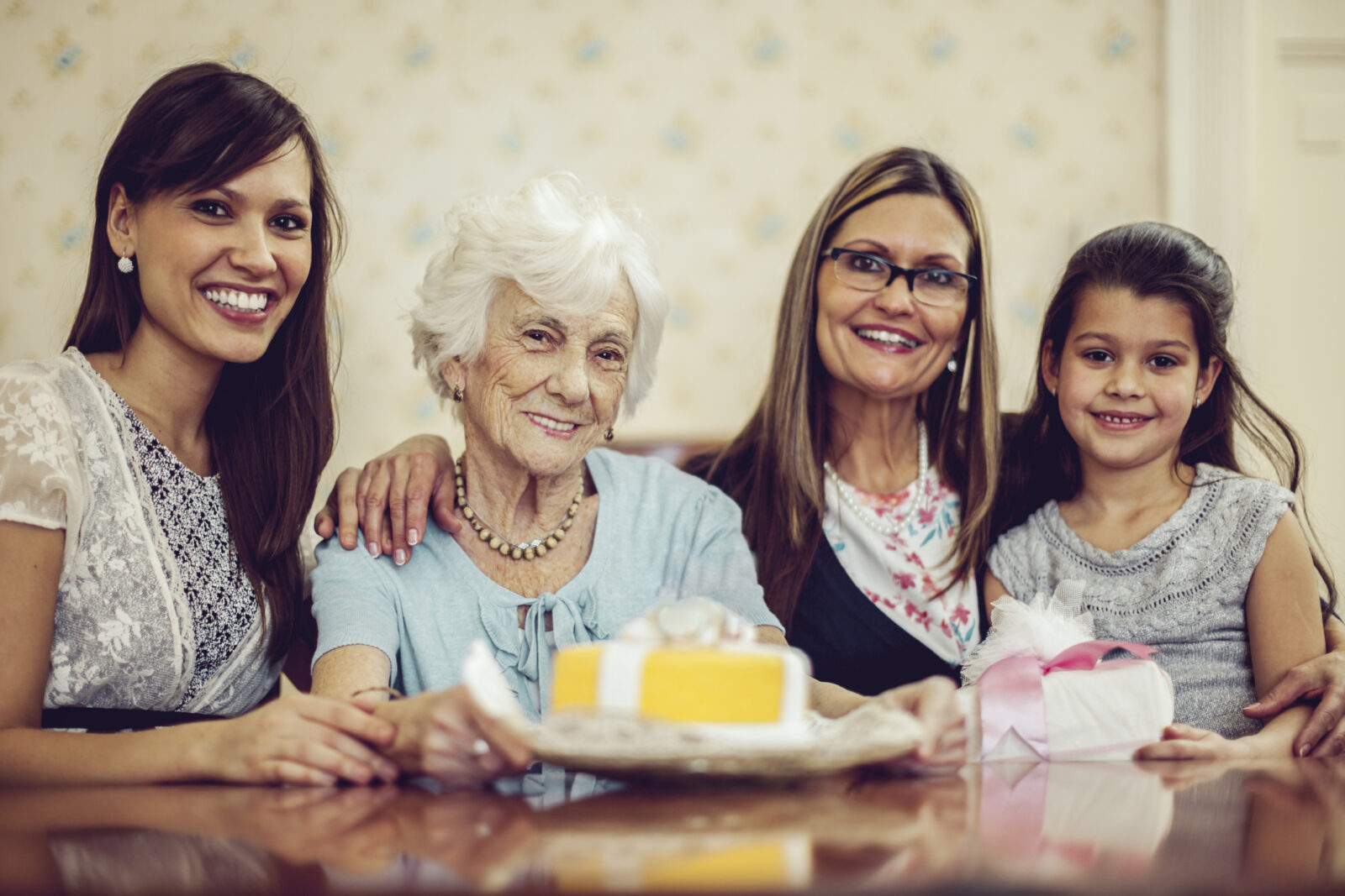Multi-generational family of females celebrate their matriarch with cake.