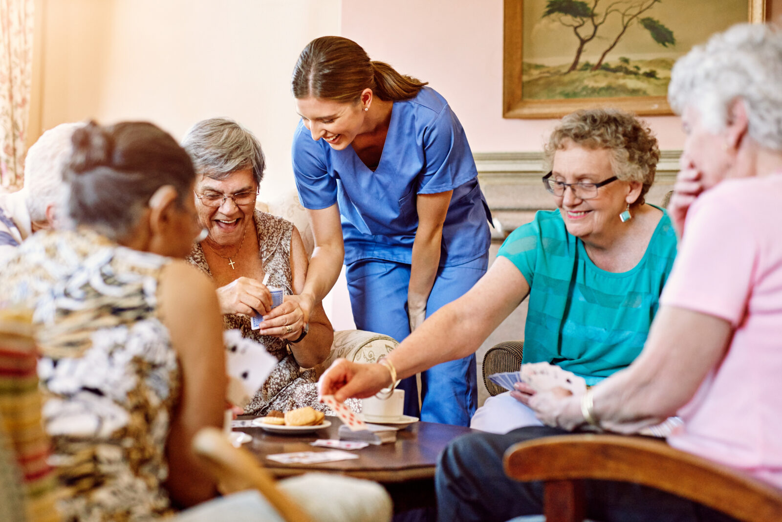 Cropped shot of seniors playing cards in their retirement home with an activity professional helping out.