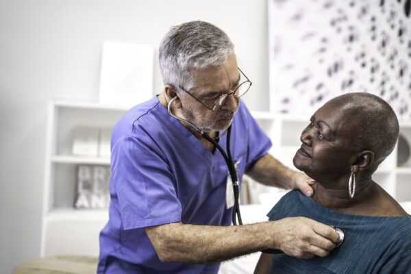 Doctor using a stethoscope listen to the heartbeat of the Black elderly patient