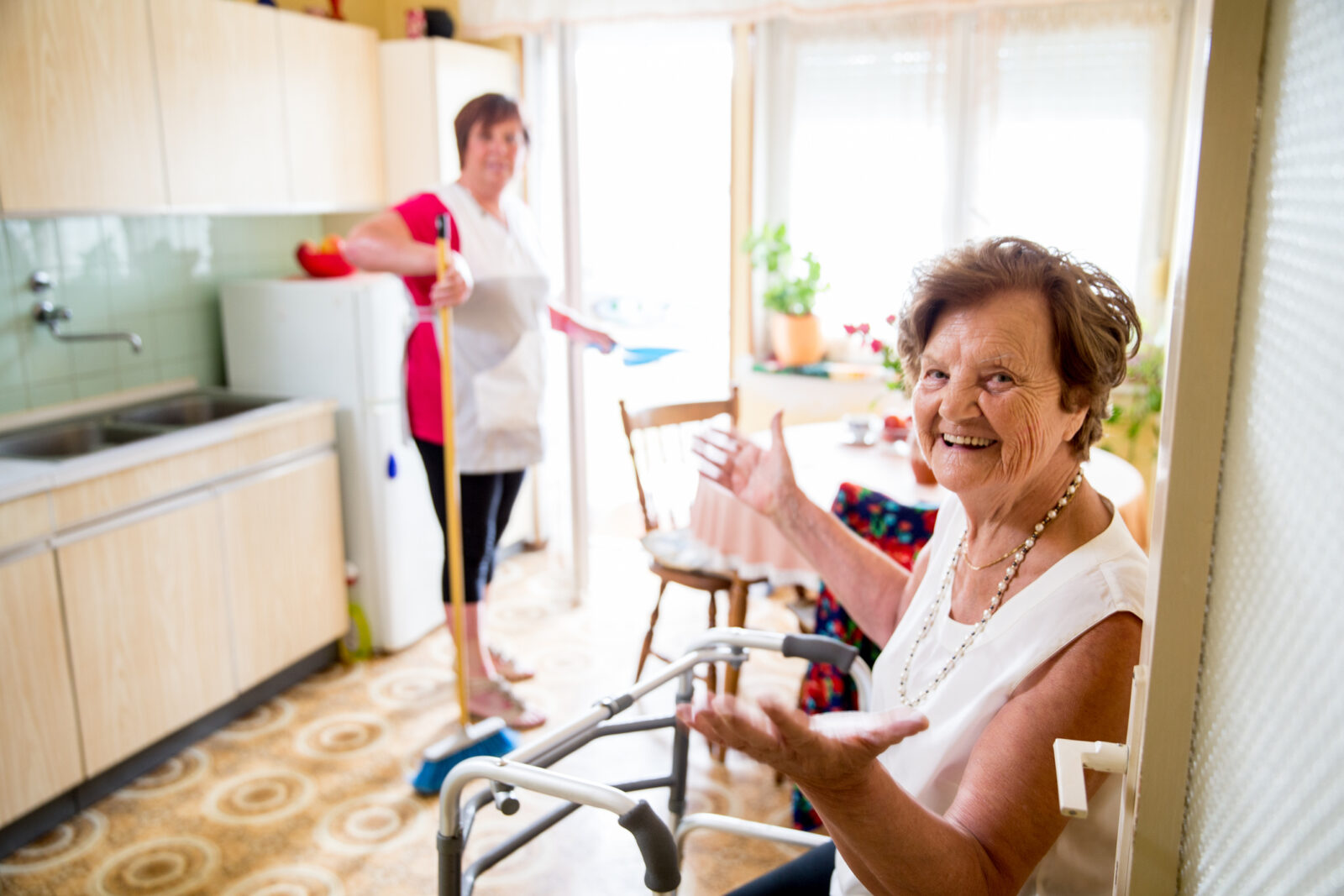 Elderly Woman talking with a daughter while she is doing chores